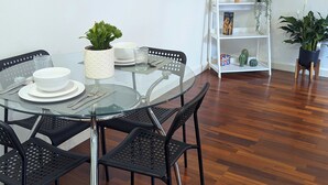 Un coin repas avec une table en verre, des chaises noires, des assiettes blanches et une plante en pot.