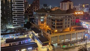 A multi-story building with a ground floor that appears to be a commercial space with shops. There are several balconies and a large open area that could be a courtyard or plaza. - Smart Homes - The Luxe Retreat (Nairobi)
