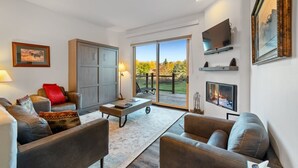 Ein modernes Wohnzimmer mit Ledersofas, einem Couchtisch und einer großen Schiebeglastür, die auf eine Terrasse führt.