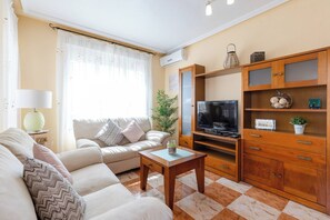 Una sala de estar con un sofá, una mesa de centro, un televisor y un aparador de madera.