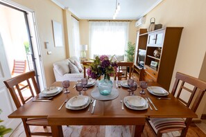 Une table à manger dressée pour six personnes, avec des assiettes, des couverts et un vase de fleurs.