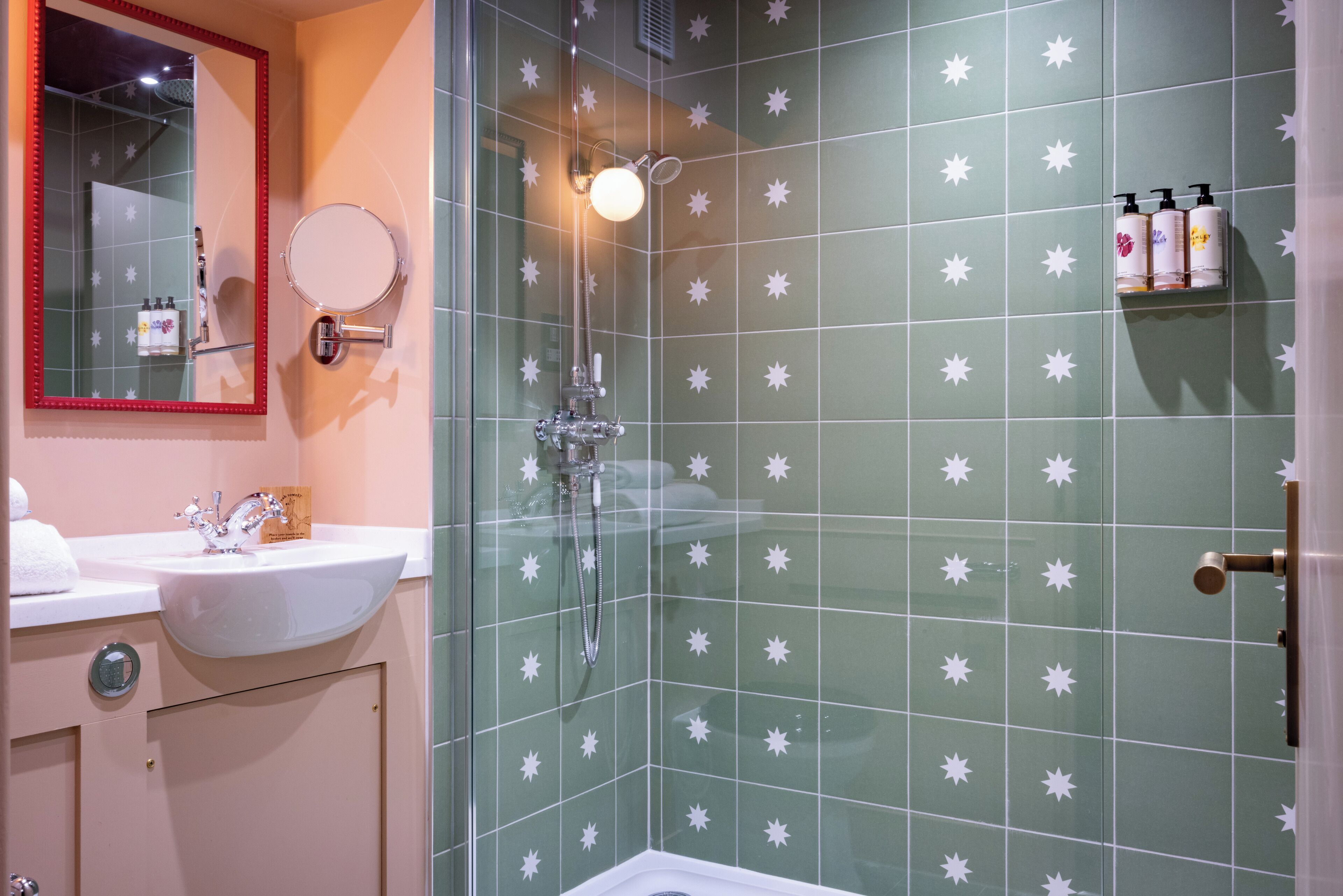 Un baño con lavamanos, espejo y zona de ducha.