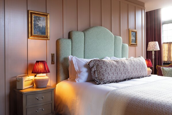 A hotel room with a large bed, a nightstand with a lamp, a radio, and a drawer.