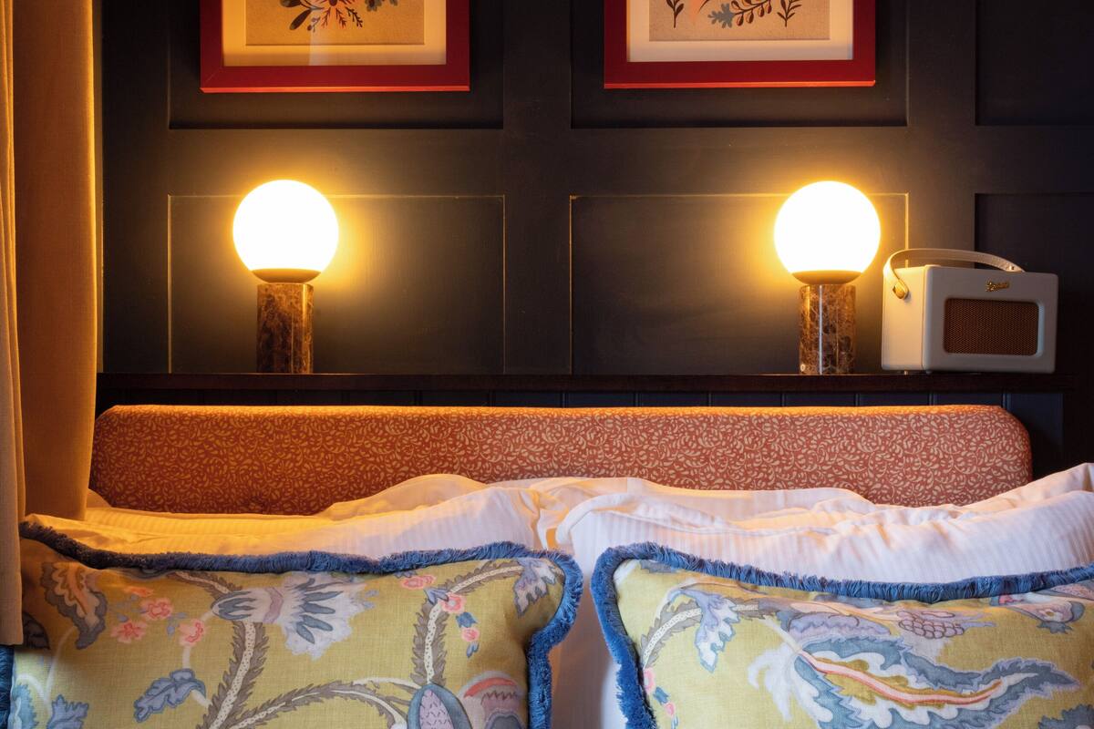 A neatly made bed with patterned pillows and a headboard with two framed artworks.
