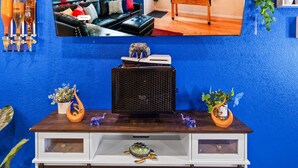 A room with a blue wall, a wooden cabinet with decorative items, and a framed picture above it. - 420Friendly Game Arcade DancePole Airport DIA (Denver)