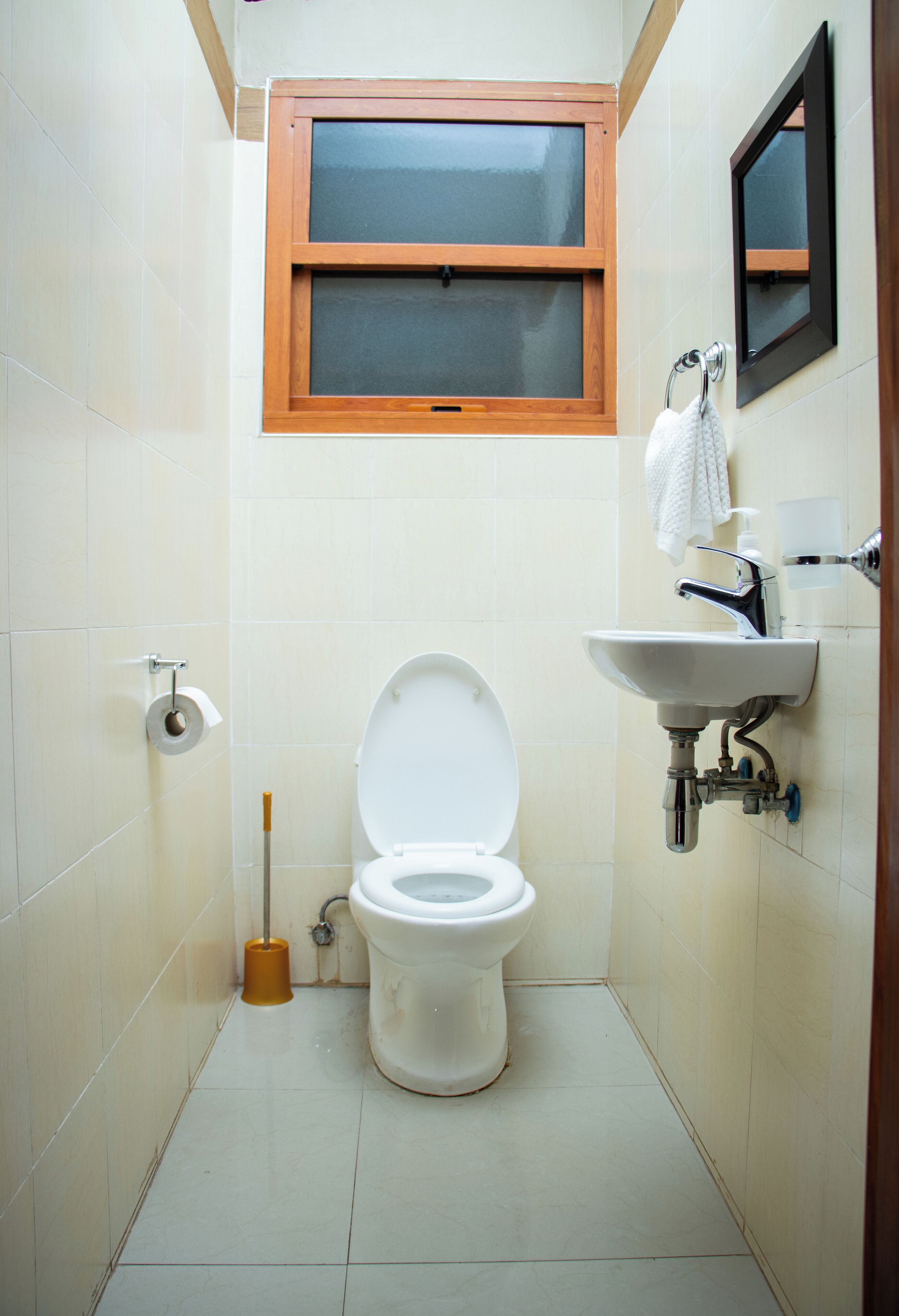A small, clean bathroom with a toilet, sink, and window.