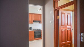 Um corredor leva a uma cozinha com armários de madeira e um fogão.