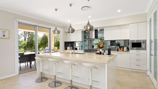 A modern kitchen with a central island, bar stools, stainless steel appliances, and pendant lighting. - Our Multi-Award Winning Hawkesbury Holiday Home (East Kurrajong)