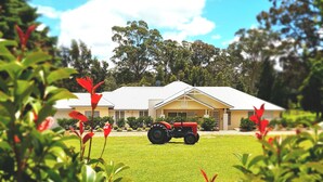A house with a well-maintained lawn and a red tractor parked in front. - Our Multi-Award Winning Hawkesbury Holiday Home (East Kurrajong)