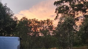 A hot tub with a clear view of the surrounding trees and a sunset in the background. - Our Multi-Award Winning Hawkesbury Holiday Home (East Kurrajong)