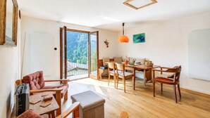 Una sala de estar moderna con comedor, muebles de madera y un amplio ventanal con vista a árboles.