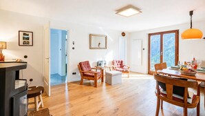 Un vaste espace de vie doté d’un plancher en bois, d’une table à manger pour quatre personnes et d’une grande fenêtre donnant sur l’extérieur.