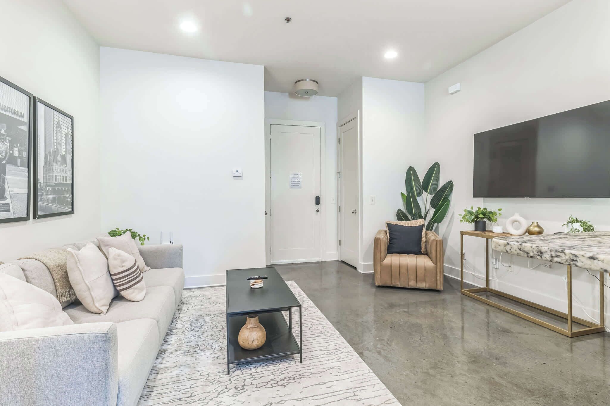A modern living room with a sofa, coffee table, and a TV mounted on the wall.