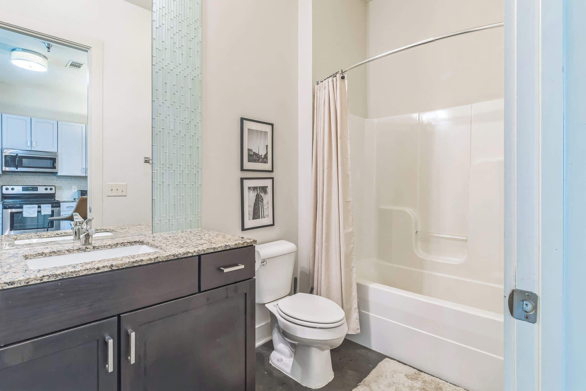 Een moderne badkamer met een wastafelmeubel met dubbele wastafel, een toilet en een inloopdouche.