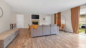 A modern living room with a grey sofa, a small table, and a fireplace. - Bright & Bold Retreat in Tulsa, OK (Tulsa)