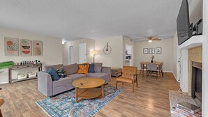 A living room with a sofa, coffee table, and armchairs, a dining area with a table and chairs, and a fireplace. - Bright & Bold Retreat in Tulsa, OK (Tulsa)