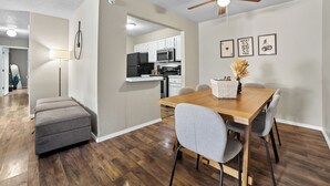 A modern kitchen with white cabinets, a wooden dining table, and a ceiling fan. - Bright & Bold Retreat in Tulsa, OK (Tulsa)