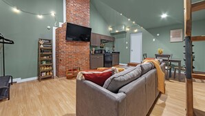 A cozy living room with a brick fireplace, a grey sofa, and a dining area with a table and chairs. - Lovely Little Loft-Style 2-Bedroom in Tulsa (Tulsa)