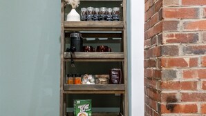 A wooden shelf with various coffee products and bags against a brick wall. - Lovely Little Loft-Style 2-Bedroom in Tulsa (Tulsa)