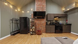 A compact living space with a kitchenette, a sofa, a TV, and a brick fireplace. - Lovely Little Loft-Style 2-Bedroom in Tulsa (Tulsa)