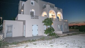 A two-story building with a light-colored facade, multiple windows, and a balcony. - Villa Anna with Panoramic view (Santorini)
