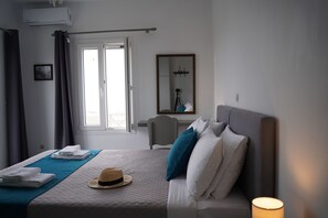 Habitación de hotel con cama, ventana, espejo y lámpara de noche.