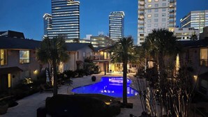 Zona residencial con piscina, palmeras y edificios modernos al fondo.