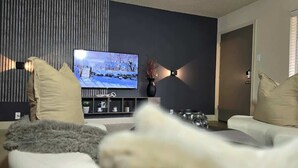 Una sala de estar moderna con un televisor de pantalla plana, un sofá y un jarrón decorativo.