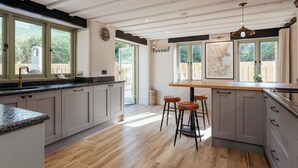 Une cuisine moderne dotée d’un grand îlot central, de planchers en bois et offrant une vue sur l’extérieur.