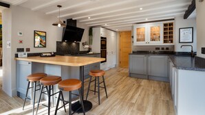 Une cuisine moderne dotée d’un îlot central, de tabourets de bar et d’un four encastré.