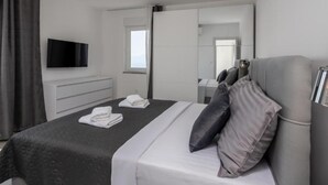Une chambre d’hôtel moderne équipée d’un lit, d’un téléviseur à écran plat fixé au mur, d’une table de chevet et d’une fenêtre avec des rideaux.