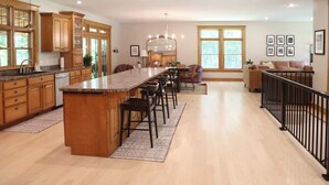 Une cuisine spacieuse avec des meubles en bois, un grand îlot central et des tabourets de bar.