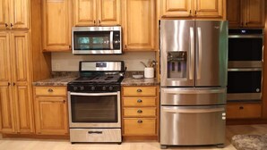Une cuisine dotée de meubles en bois, d’un réfrigérateur en acier inoxydable, d’un four à micro-ondes, d’une cuisinière et d’un four traditionnel.