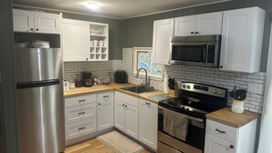 Een moderne keuken met witte kasten, roestvrijstalen apparatuur en een houten aanrecht.