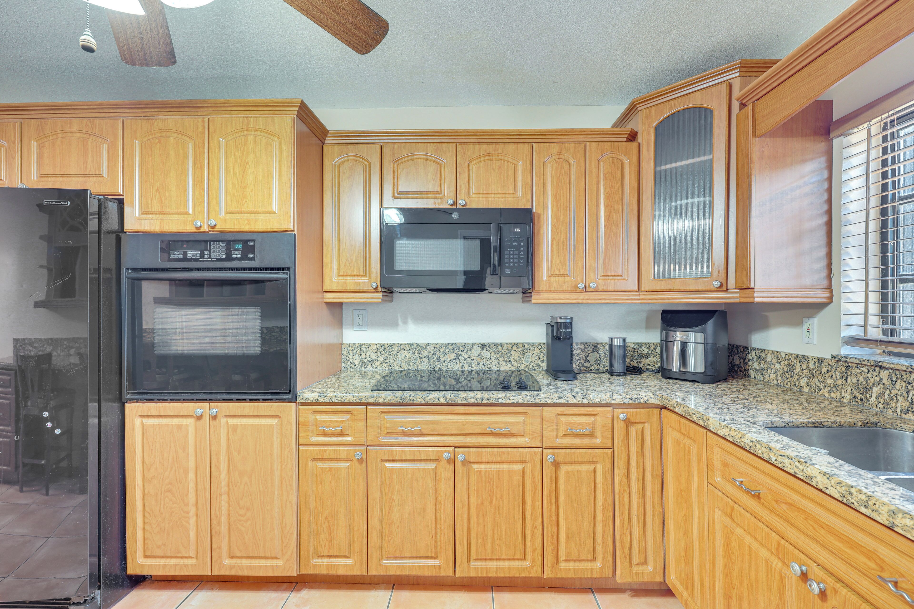 A kitchen with wooden cabinets, a stainless steel sink, a microwave, and a refrigerator.
