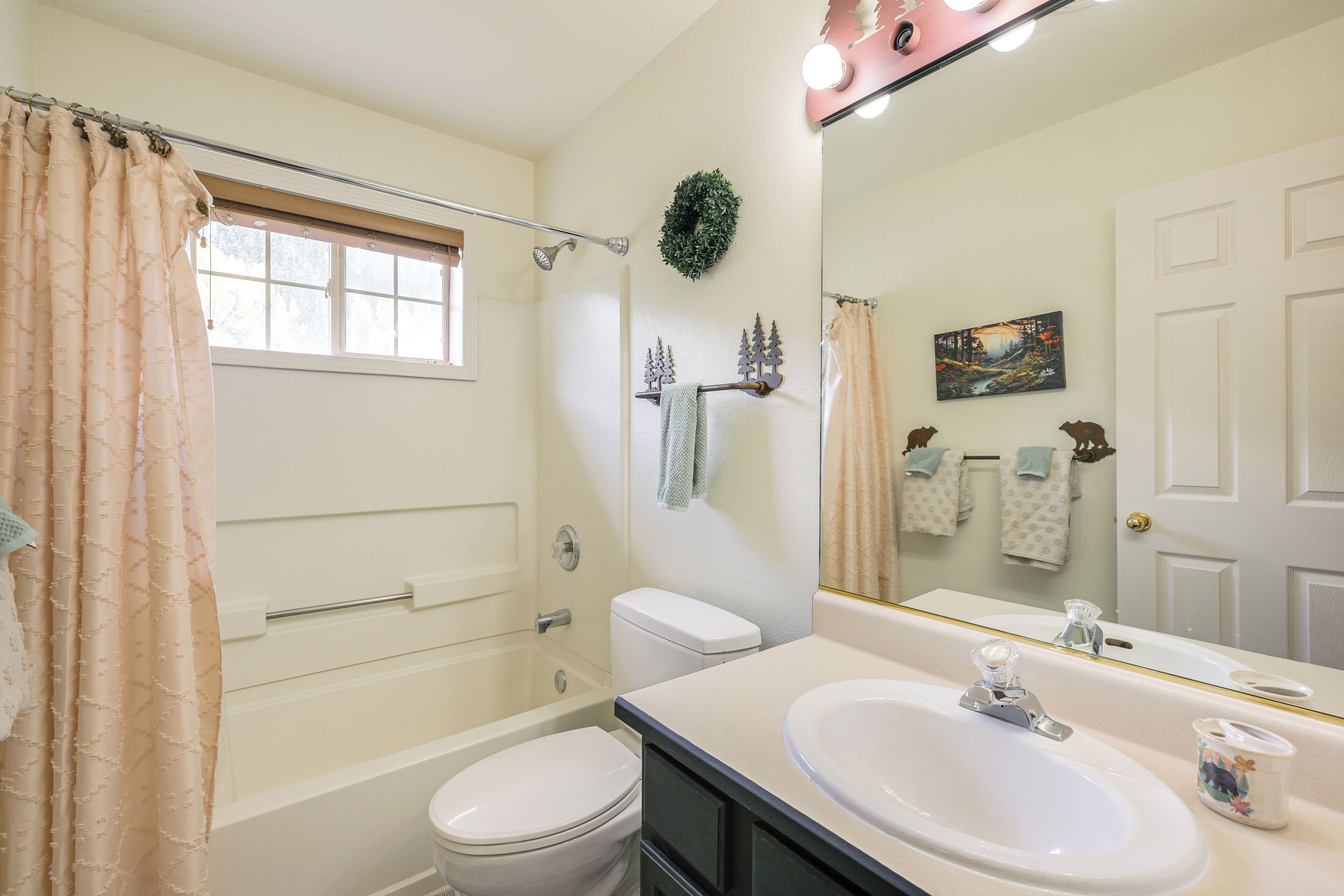 A bathroom with a bathtub, toilet, sink, and a large mirror.