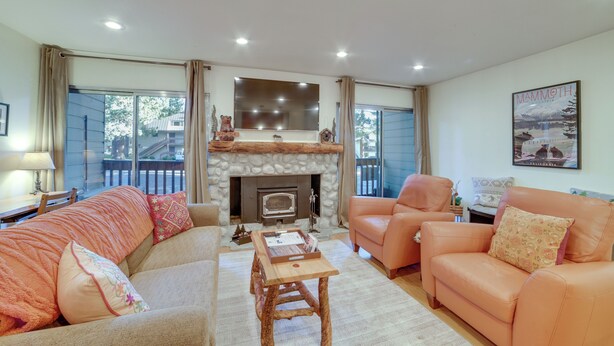 A cozy living room with a fireplace, two sofas, a coffee table, and a large window. - Ski Condo w/ Community Amenities in Mammoth Lakes! (Mammoth Lakes)