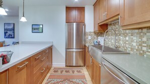 A kitchen with wooden cabinets, stainless steel appliances, a tiled backsplash, and a white countertop. - Ski Condo w/ Community Amenities in Mammoth Lakes! (Mammoth Lakes)