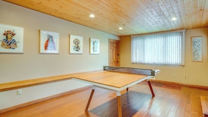Ein Zimmer mit Holzboden, einem Tischtennisplatte und Bildern an den Wänden.