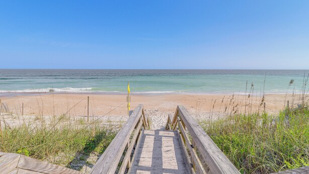 A wooden boardwalk leading to a sandy beach with the ocean in the background. - Walk to Beach: Family-friendly Surf City Condo! (Holly Ridge)