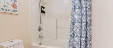 A bathroom with a bathtub, toilet, and a shower with a rain showerhead.