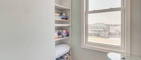 A bedroom with a large window, a glass table, and a closet with shelves.