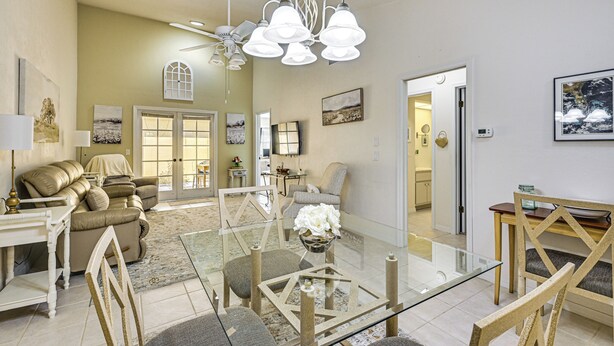A spacious living room with a glass coffee table, beige sofas, and a chandelier. - Walk to Citrus Hills Golf Club: Condo w/ Pool! (Hernando)