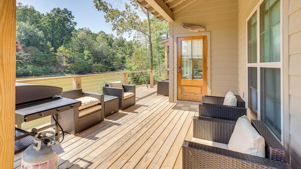 Eine Holzterrasse mit Korbmöbeln und einem Grill.