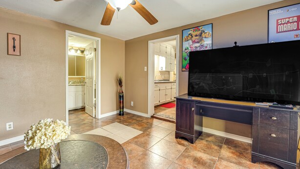 A living room with a ceiling fan, a TV, a dark wooden desk, and a vase of flowers. - Fire Pit & Grill: Victoria Home Near Downtown (Victoria)