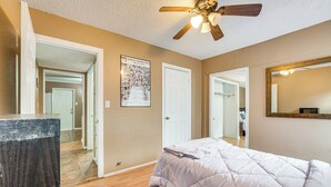 A bedroom with a bed, a ceiling fan, a mirror, and a door leading to another room. - Fire Pit & Grill: Victoria Home Near Downtown (Victoria)