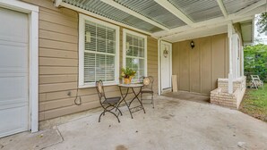 A covered porch with two metal chairs, a small round table, and a potted plant. - Fire Pit & Grill: Victoria Home Near Downtown (Victoria)