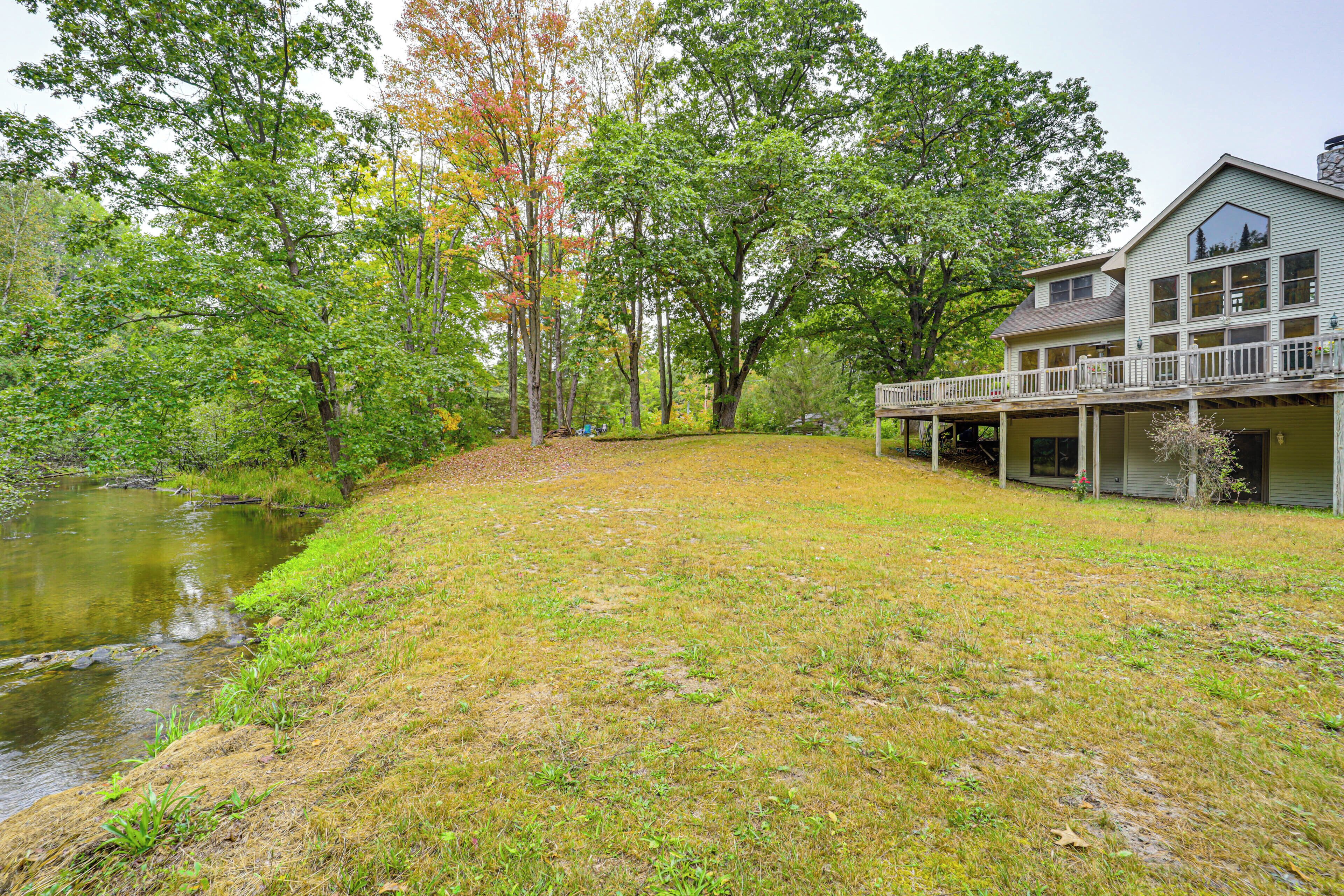 A house with a large deck overlooking a pond, surrounded by trees.