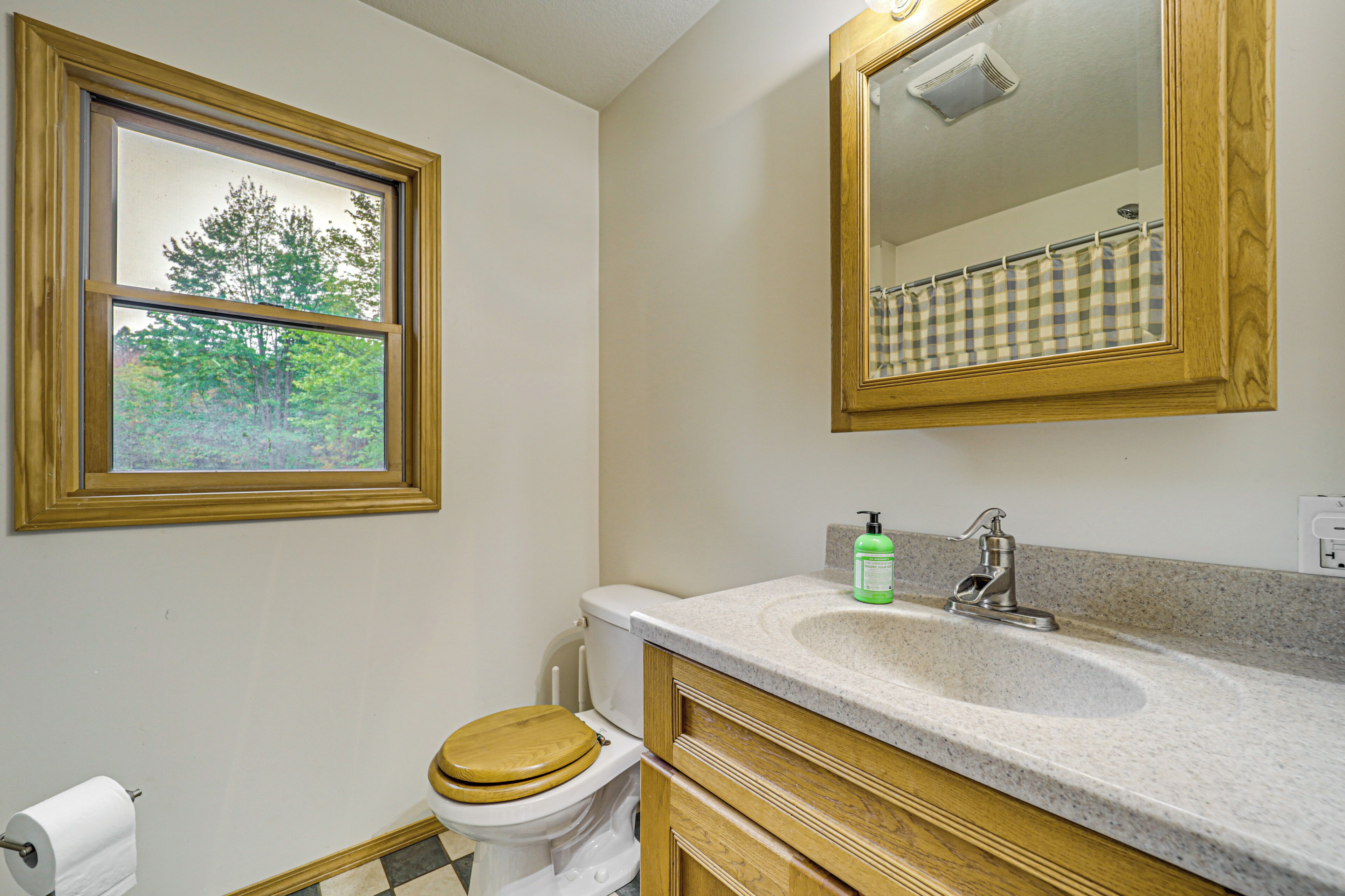 Une salle de bain équipée de toilettes, d’un lavabo, d’un miroir et d’une fenêtre.