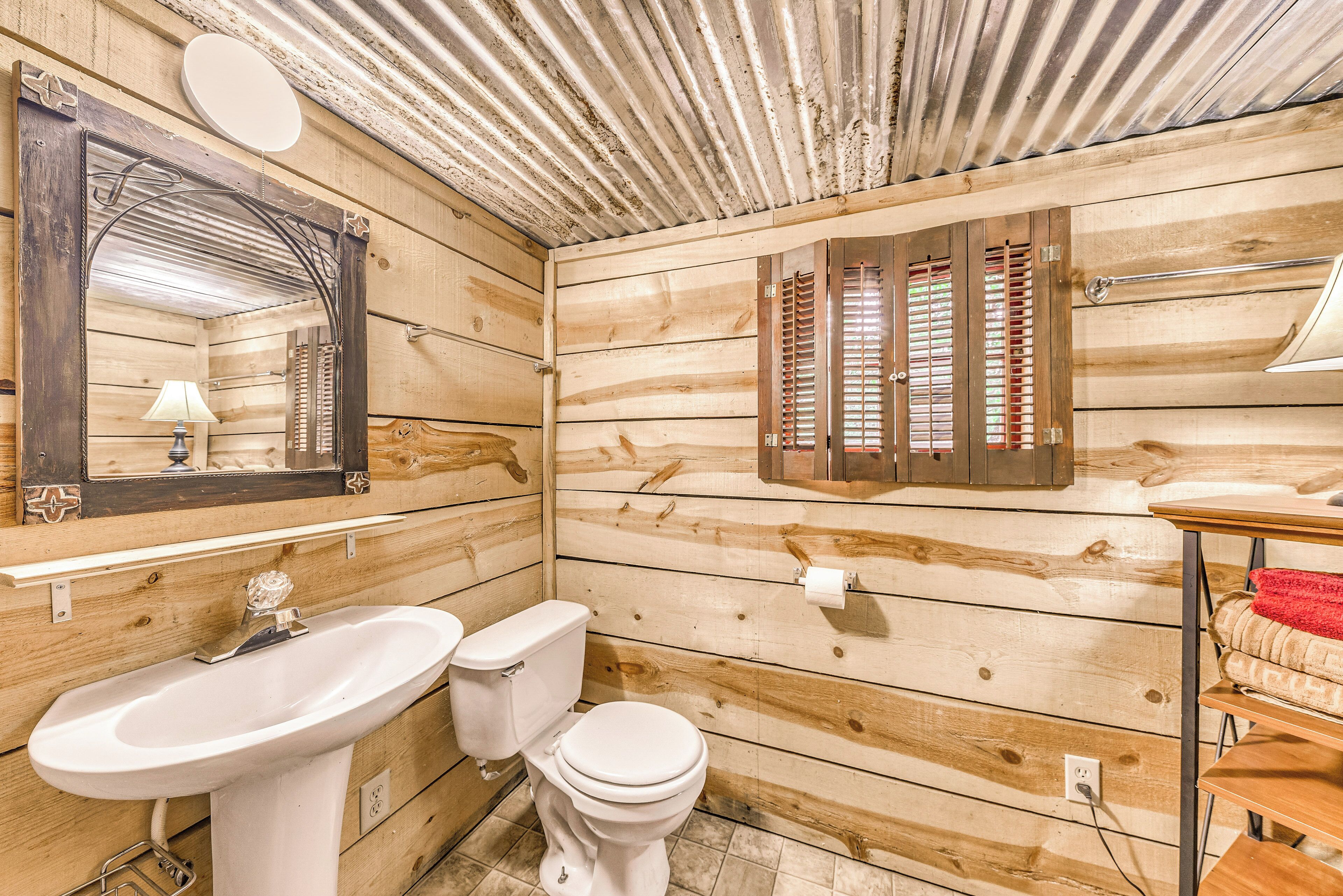 A wooden cabin bathroom with a sink, toilet, and mirror.